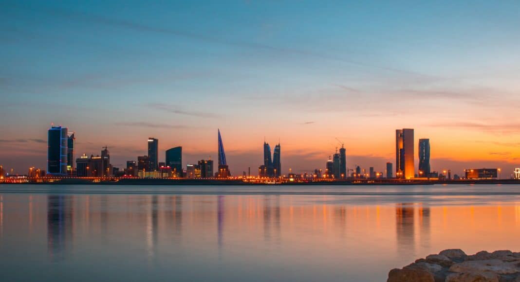 city buildings beside body of water under blue sky