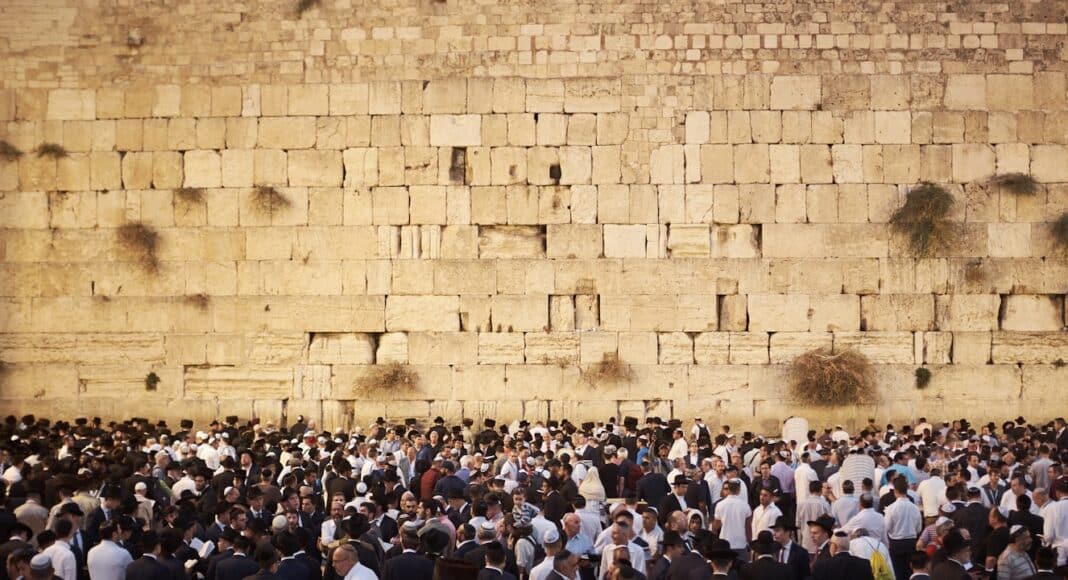 a crowd of people standing in front of a stone wall