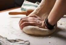 person making dough beside brown wooden rolling pin