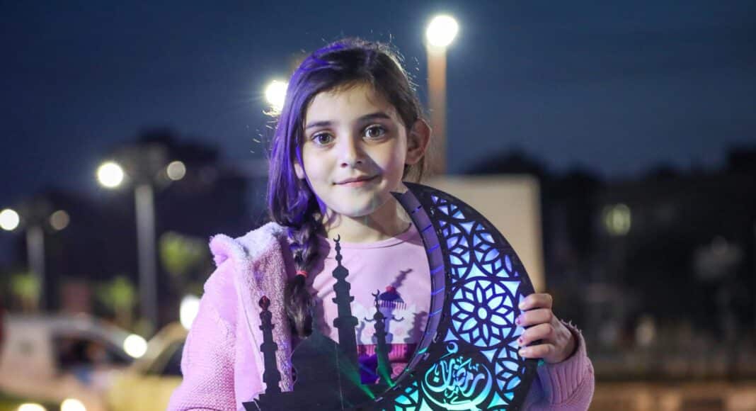a young girl holding a cutout of a tree of life