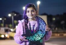 a young girl holding a cutout of a tree of life