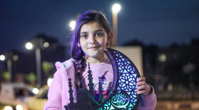 a young girl holding a cutout of a tree of life