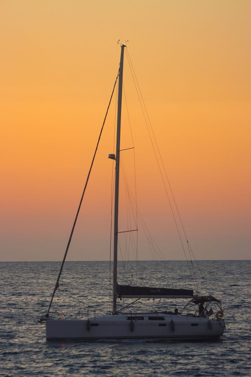 a sailboat in the ocean at sunset
