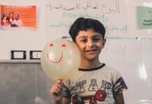 A young boy holding a balloon with a smiley face on it