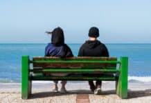 État de crise : l’Iran au bord de l’effondrement économique two people sitting on a bench looking out at the ocean