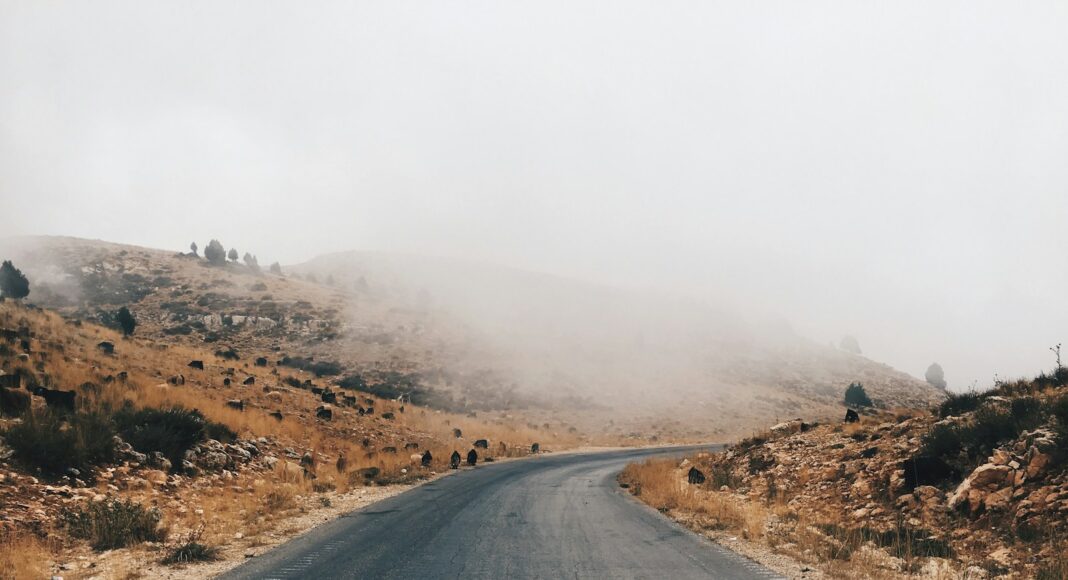 gray asphalt road near brown mountain during daytime