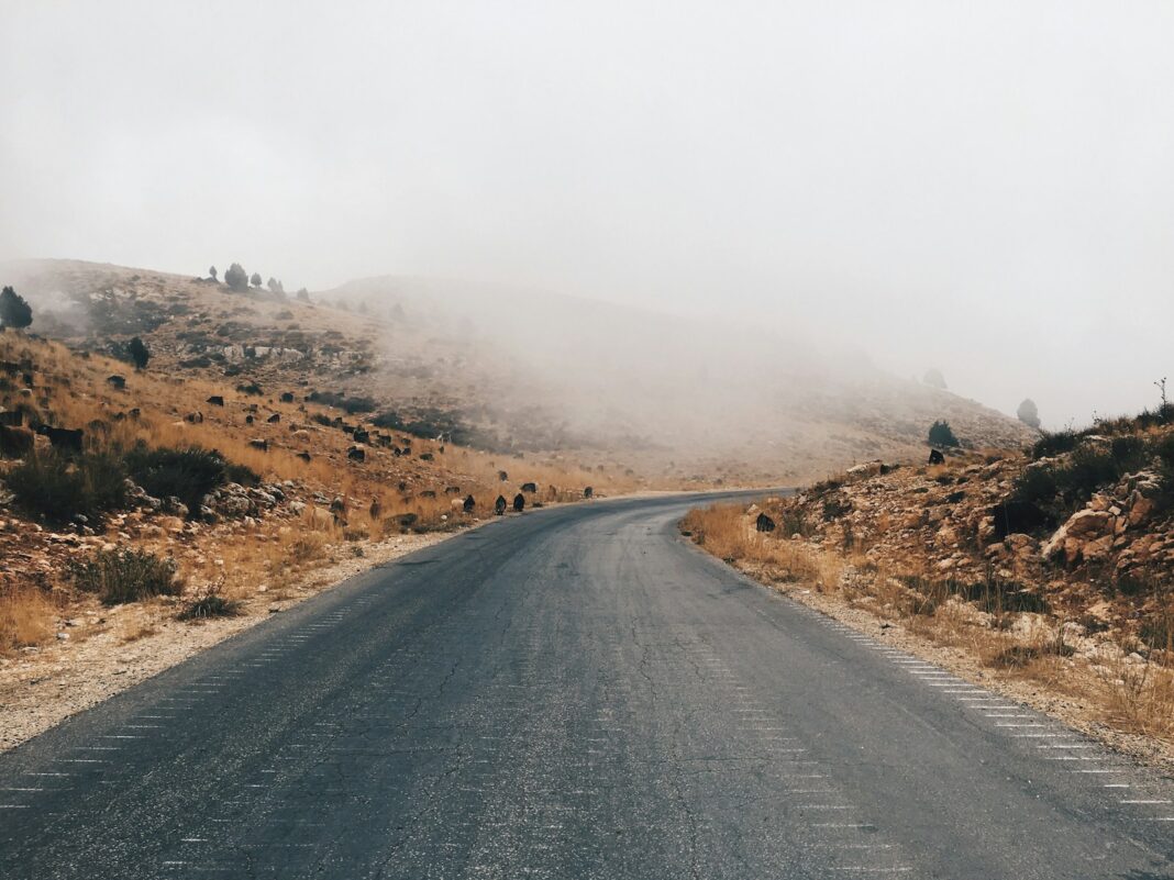 gray asphalt road near brown mountain during daytime