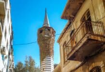 a man riding a bike down a street next to tall buildings