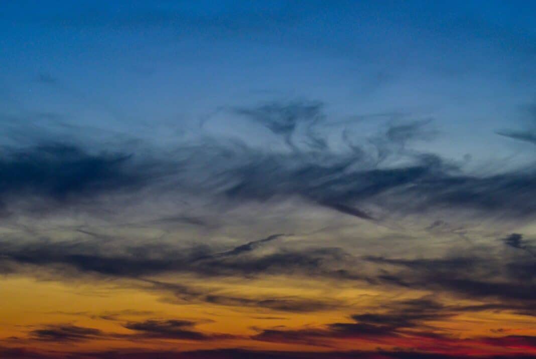 A plane flying in the sky at sunset