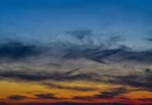 A plane flying in the sky at sunset