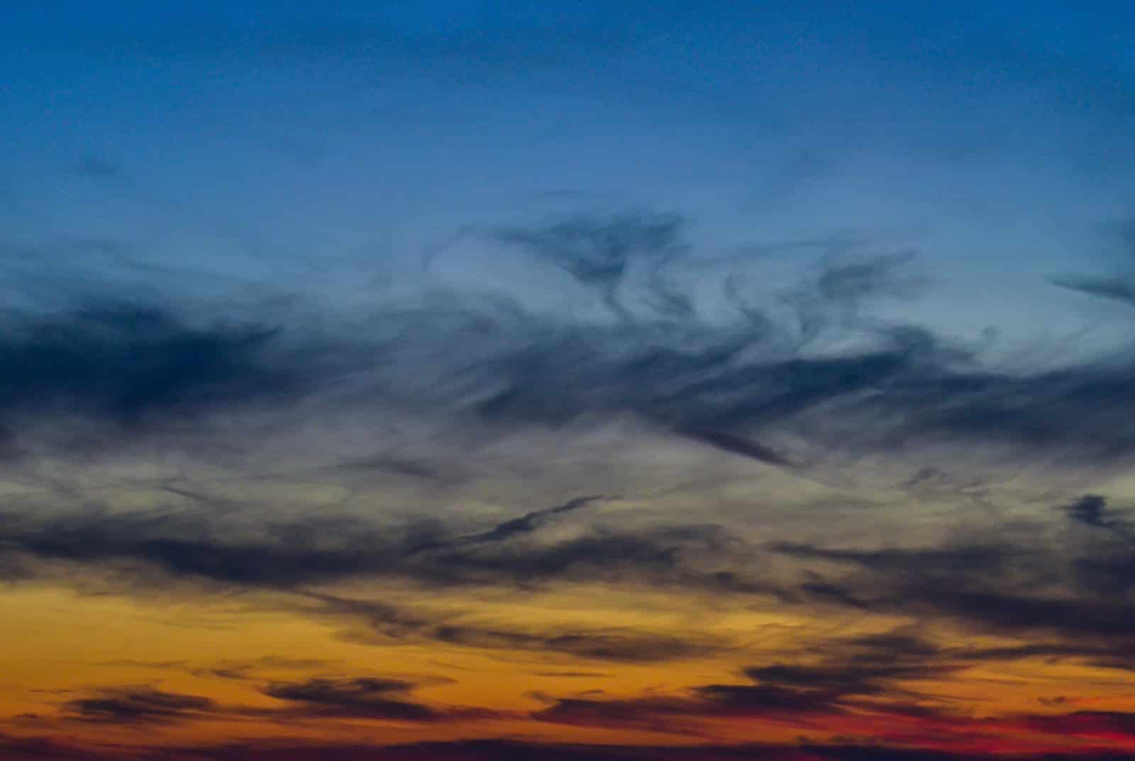 A plane flying in the sky at sunset