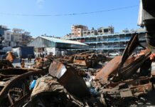 A man standing next to a pile of junk
