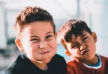 shallow focus photography of two boys doing wacky faces