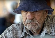 An old man wearing a hat and looking at the camera