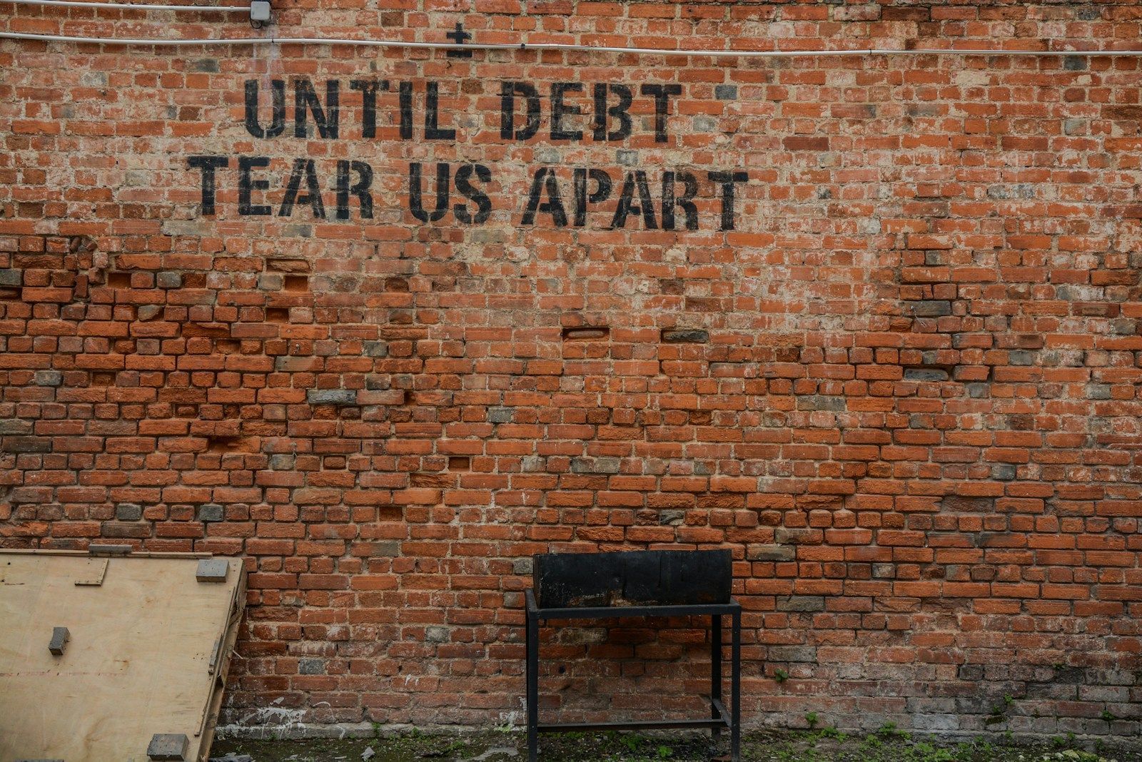 L’endettement croissant de l’Occident et des États-Unis : un engrenage vers la récession et le risque systémique ? Until debt tear us apart printed red brick wall at daytime