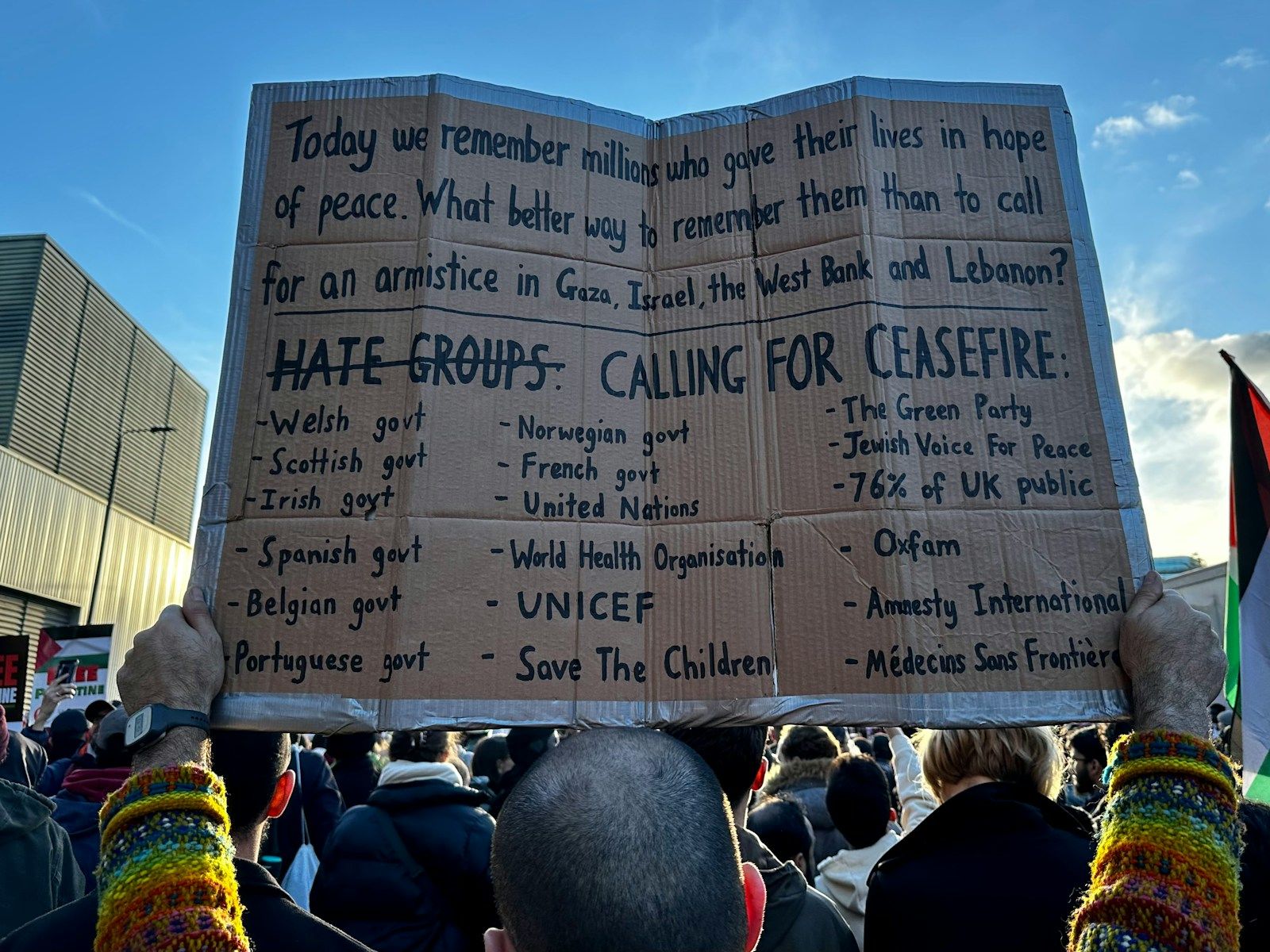 Israël et le Hamas : tensions autour du cessez-le-feu à Gaza et défis de mise en œuvre a person holding a cardboard sign in front of a crowd