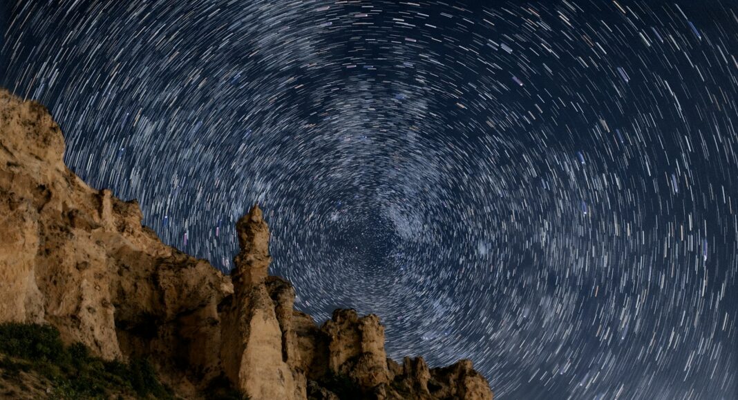 The night sky is full of stars above a mountain