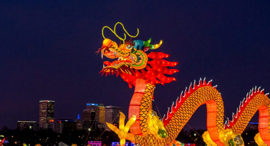 people walking on street with dragon statue during night time