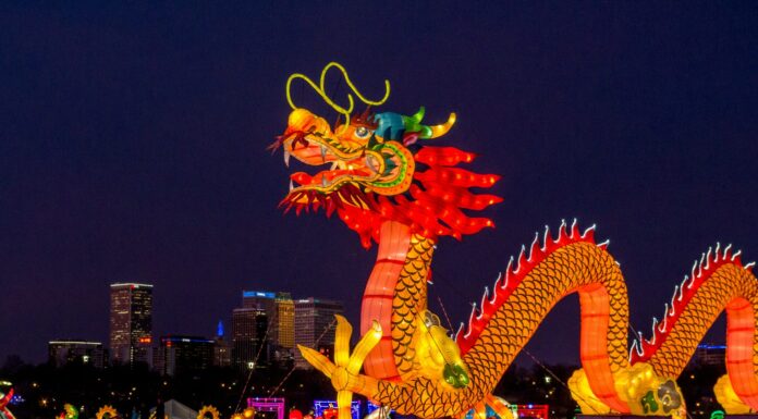 people walking on street with dragon statue during night time
