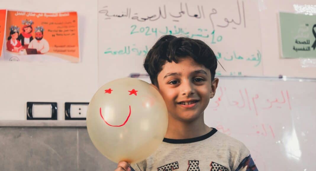 A young boy holding a balloon with a smiley face on it