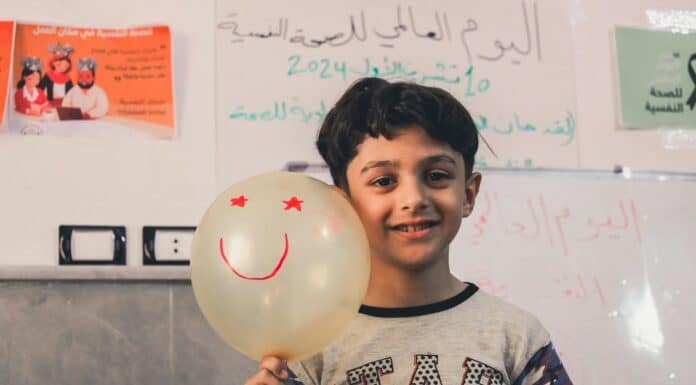 A young boy holding a balloon with a smiley face on it
