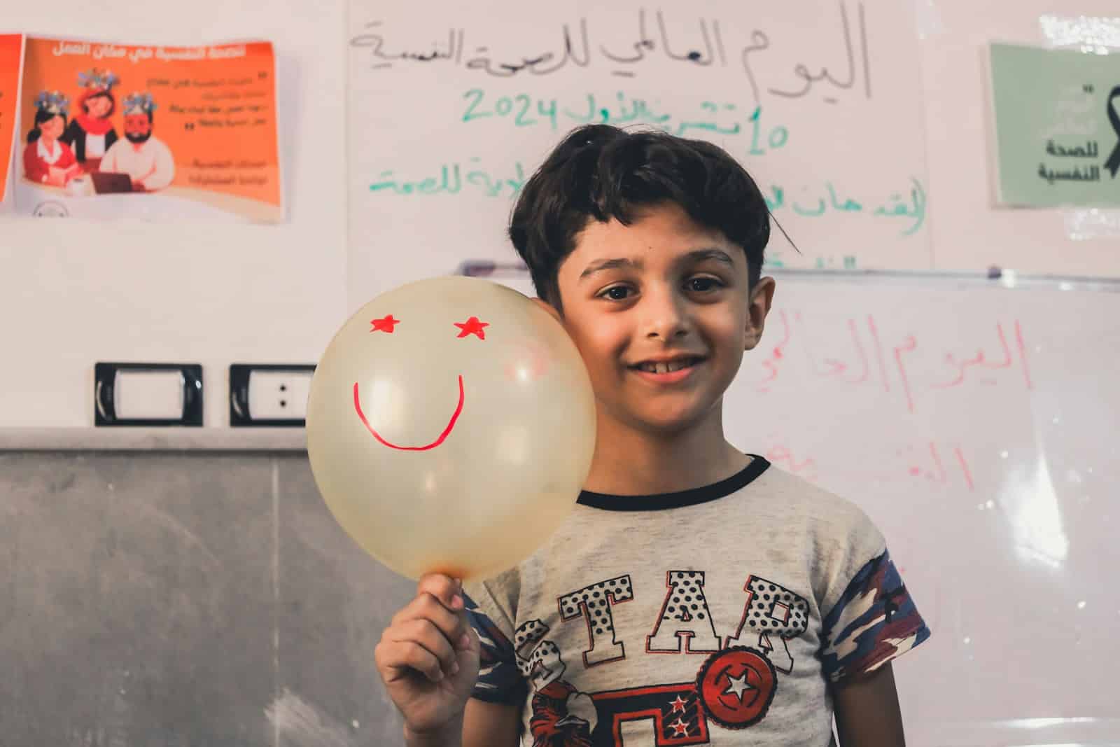 A young boy holding a balloon with a smiley face on it