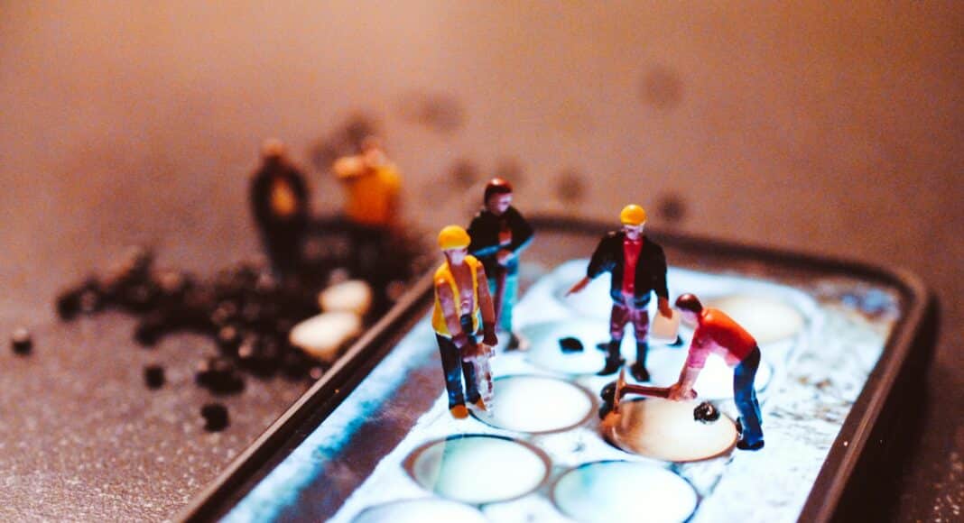 tiny model construction workers, working on a mobile phone screen