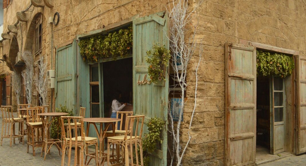 a man standing outside of a building next to tables and chairs