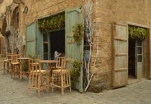 Dans la presse: Le Liban des années 60 doit renaître a man standing outside of a building next to tables and chairs