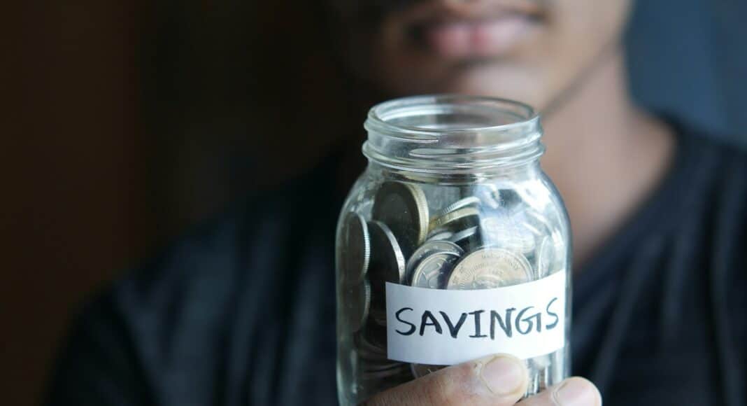 a man holding a jar with a savings label on it