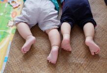 baby in white shirt and black pants lying on brown carpet