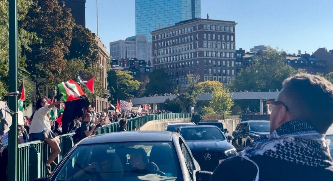 A crowd of people walking down a street next to tall buildings