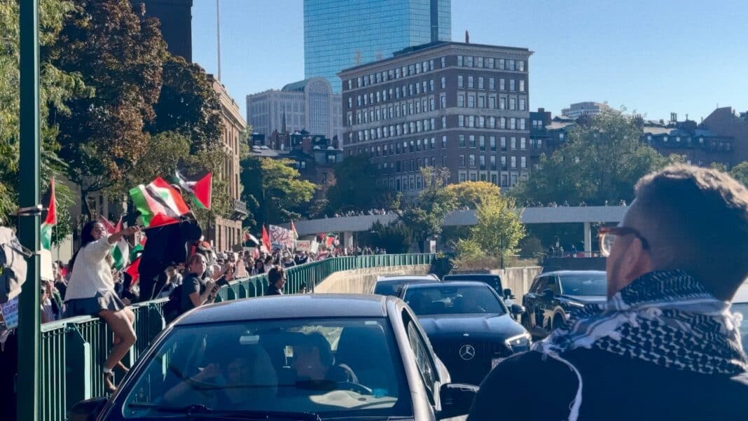 A crowd of people walking down a street next to tall buildings