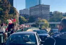 A crowd of people walking down a street next to tall buildings