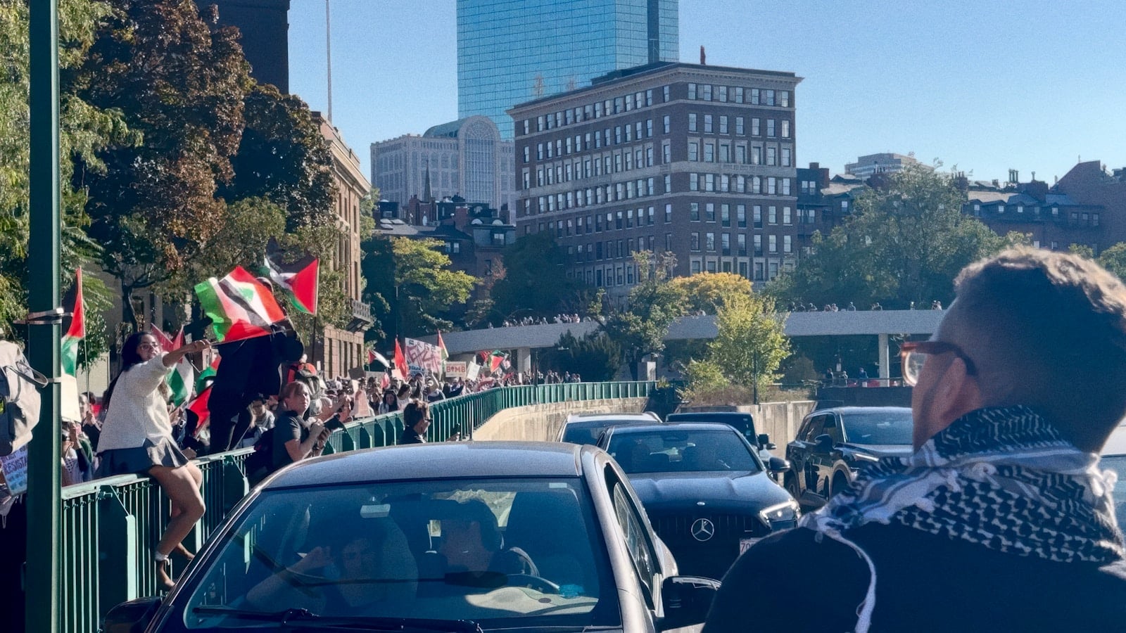 A crowd of people walking down a street next to tall buildings