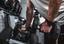 person in gray shirt holding black dumbbell
