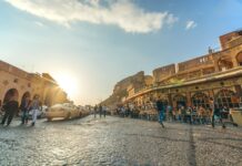 people walking on beach near brown concrete building during daytime