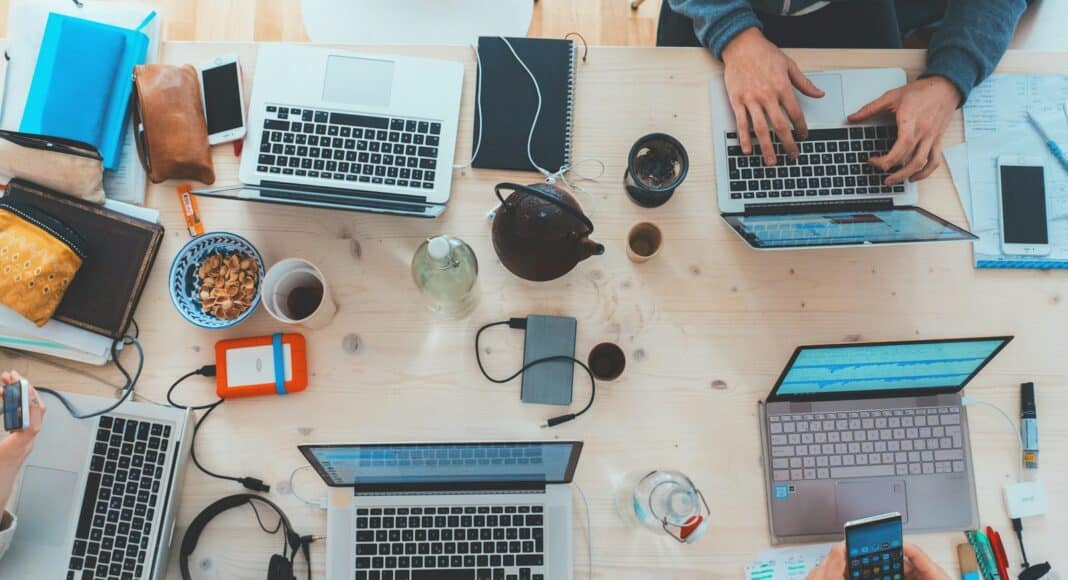 people sitting down near table with assorted laptop computers