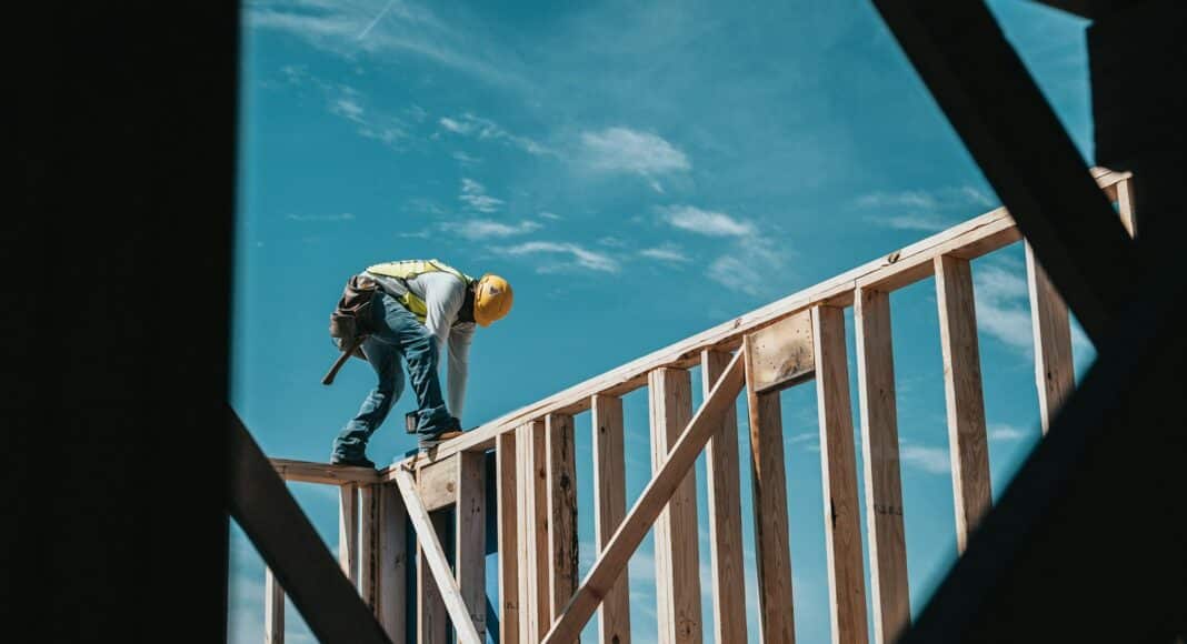 man in yellow shirt and blue denim jeans jumping on brown wooden railings under blue and
