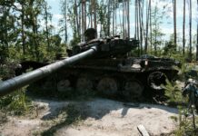 an old tank sitting in the middle of a forest