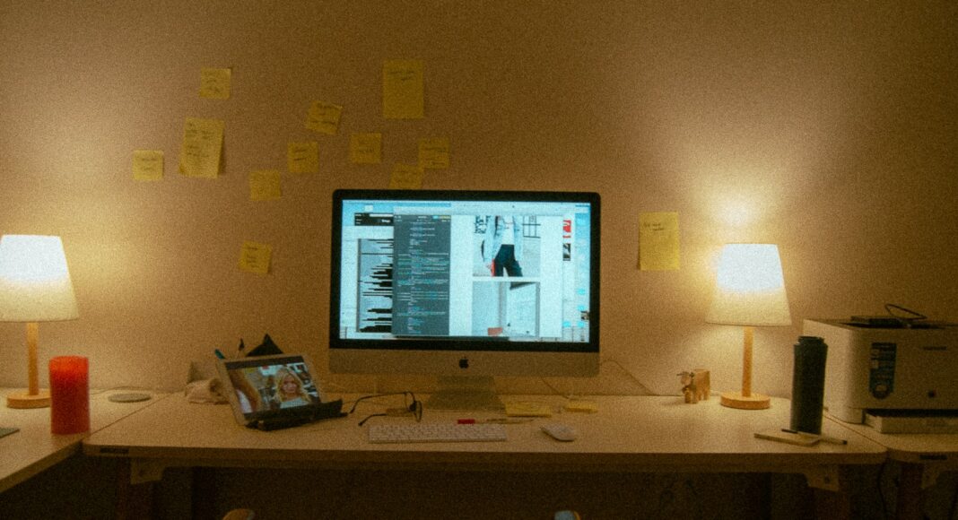A computer desk with lamps and post-it notes.
