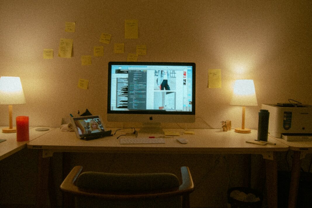 A computer desk with lamps and post-it notes.