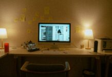 A computer desk with lamps and post-it notes.