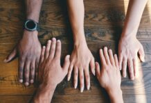 five human hands on brown surface