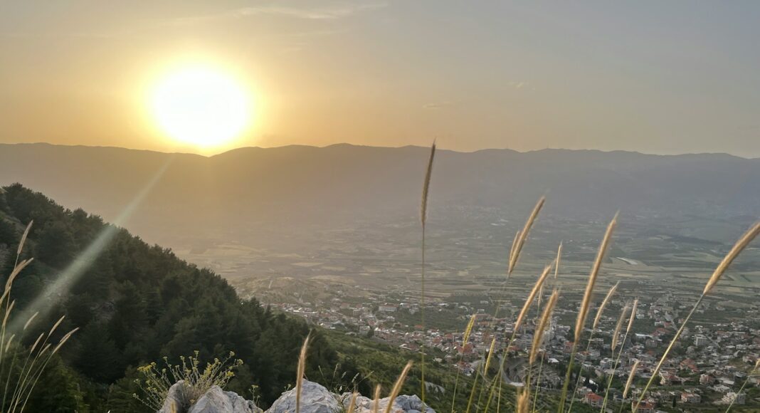 the sun is setting over the mountains and valleys