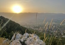 the sun is setting over the mountains and valleys