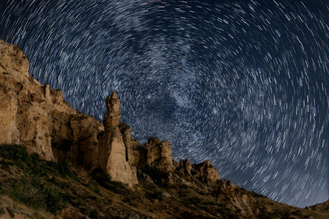 The night sky is full of stars above a mountain