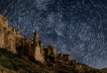 The night sky is full of stars above a mountain