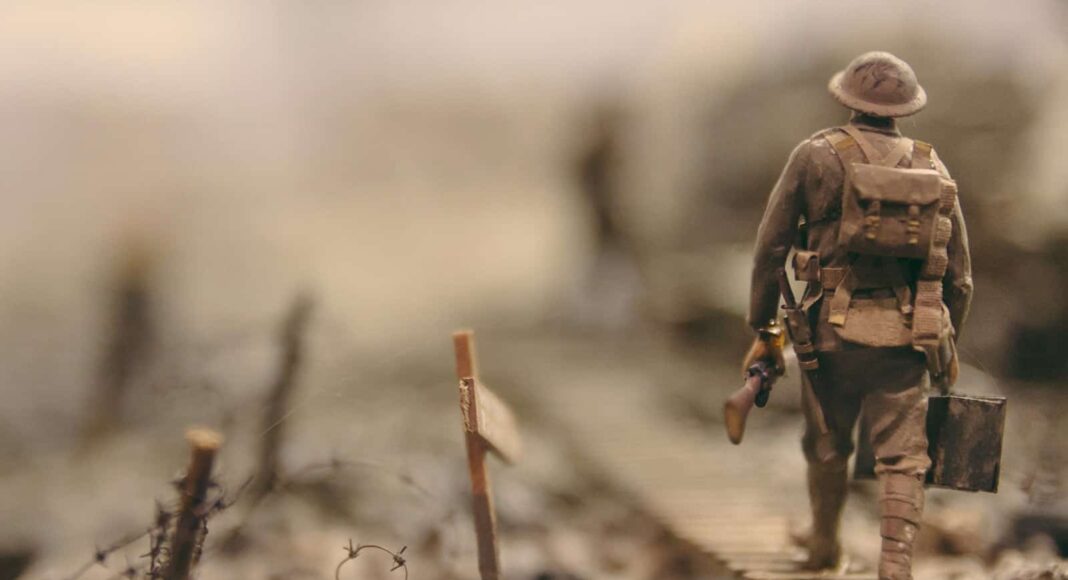 soldier walking on wooden pathway surrounded with barbwire selective focus photography