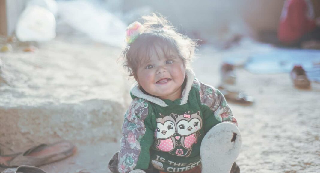 a little girl sitting on the ground with a stuffed animal
